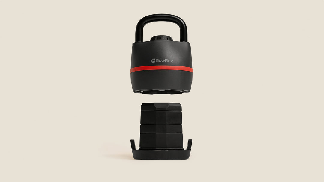 The BowFlex SelectTech 840 Kettlebell lifted above its weight plates.