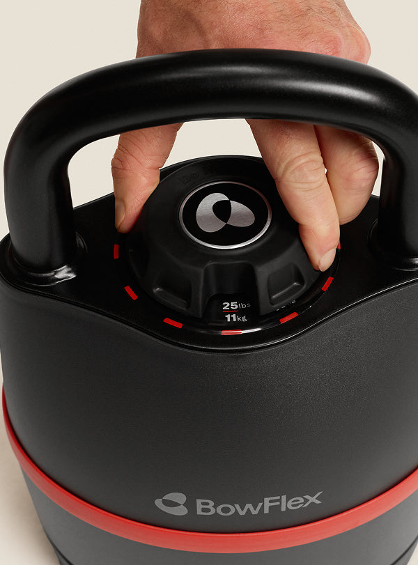 A hand adjusting the weight selection dial on the BowFlex SelectTech 840 Kettlebell.