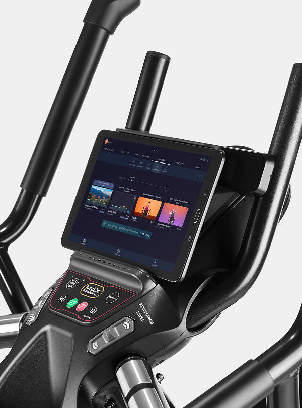 A tablet displaying a JRNY app screen placed on the BowFlex Max Trainer M6 media shelf.