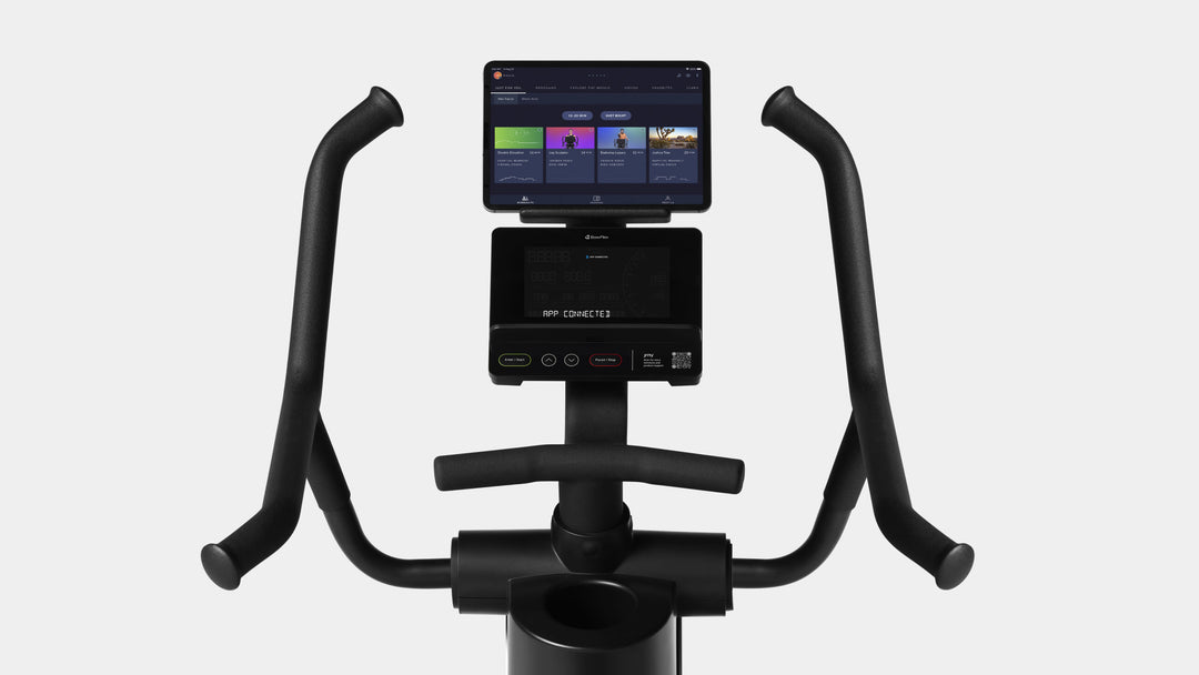 The BowFlex Max Trainer SEi console and 4-grip handlebars with a tablet on its media holder displaying a JRNY app screen.
