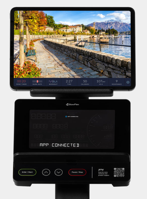 Tablet displaying a JRNY app screen placed on the BowFlex Max Trainer SEi console media shelf.
