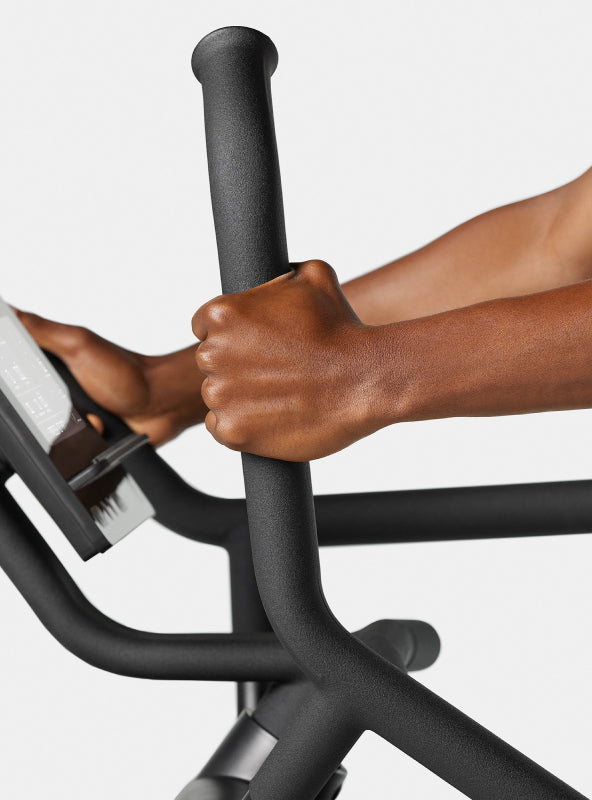 Close up of hands on the BowFlex Max Trainer SEi 4-grip handlebars against a light gray background.