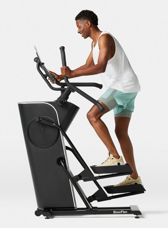 Side view of a man exercising on the BowFlex Max Trainer SEi against a white background.