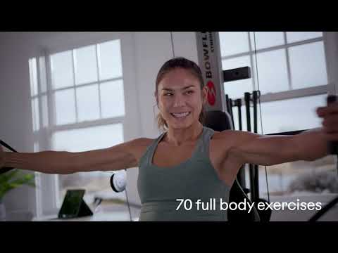 Woman smiling while exercising on the BowFlex Xtreme 2 SE Home Gym in a home setting.