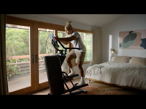 Person working out on a BowFlex Max Trainer SEi in a home bedroom setting.