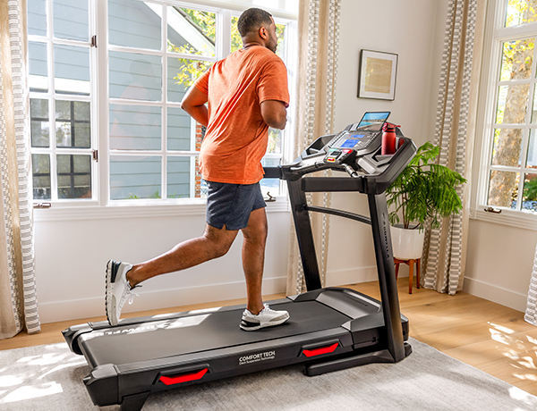man running on a BXT8Ji Treadmill in a sunny room